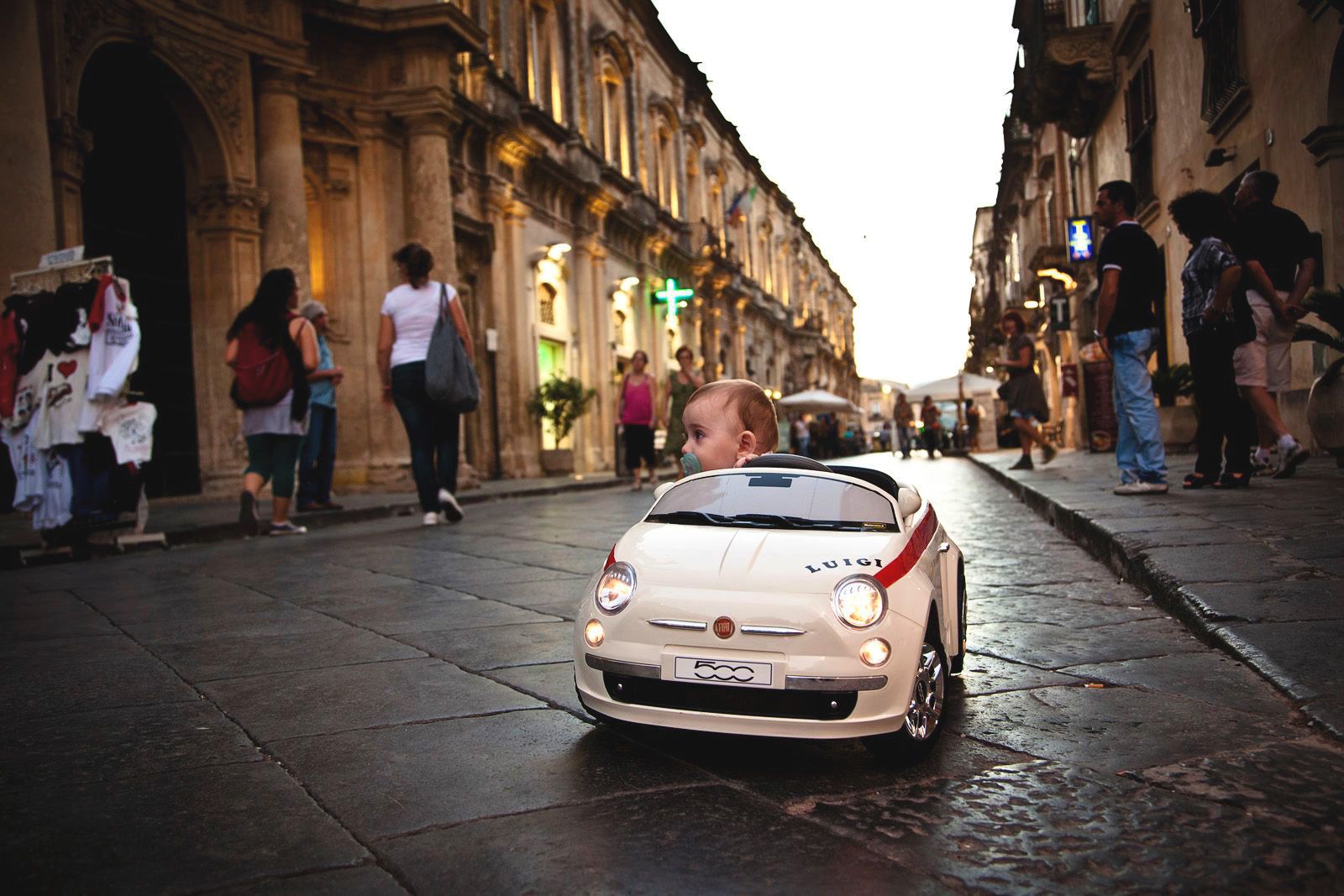 Little boy on his favorite remote controlled Fiat 500 on the old streets in Noto, Sicily