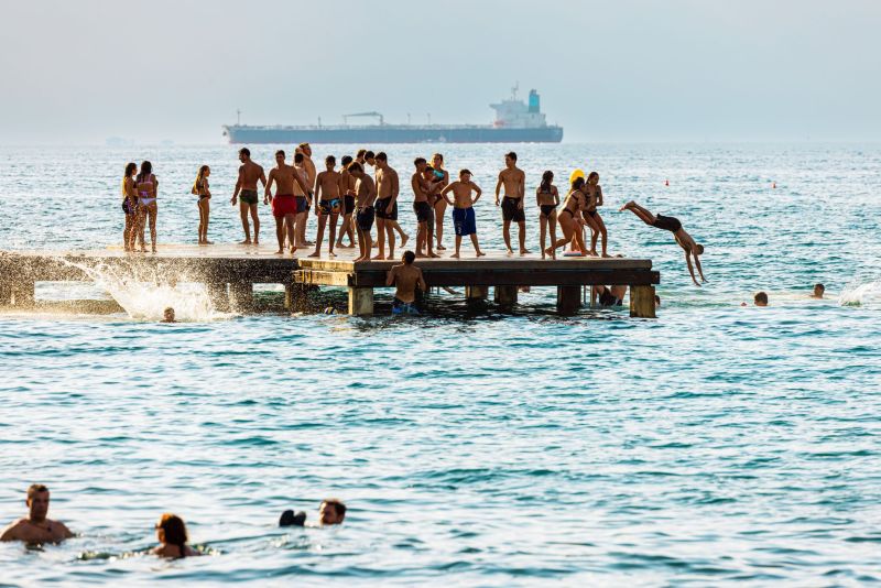 Young locals enjoying the summer, jumping from a floating pier at the Golfo di Trieste