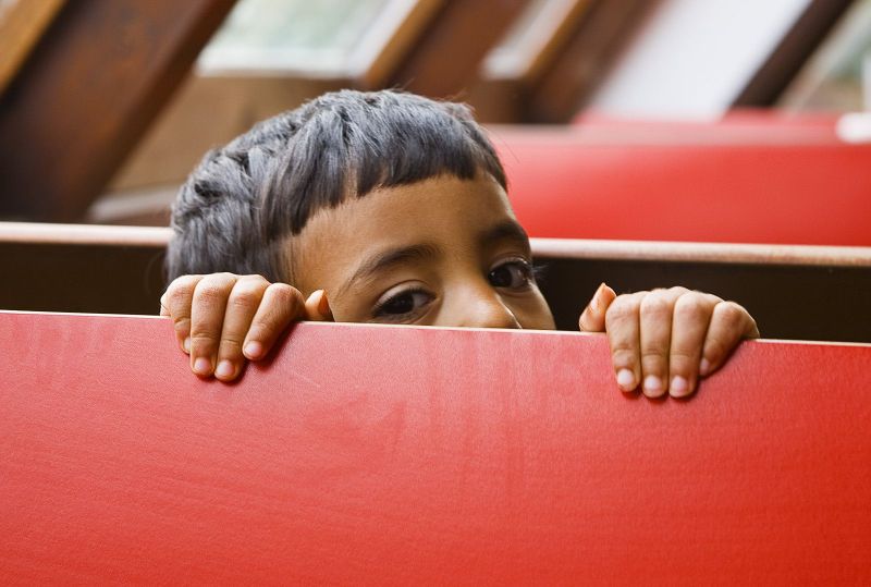 Shy boy hides behind a red bench in a diner, Albuquerque, New Mexico